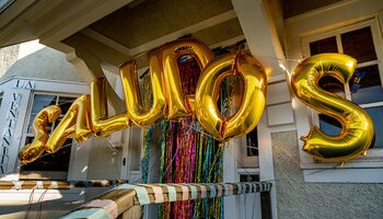 Gold balloon letters spell out "SALUDOS" outside the front door of the La Casa Cultural Latina house