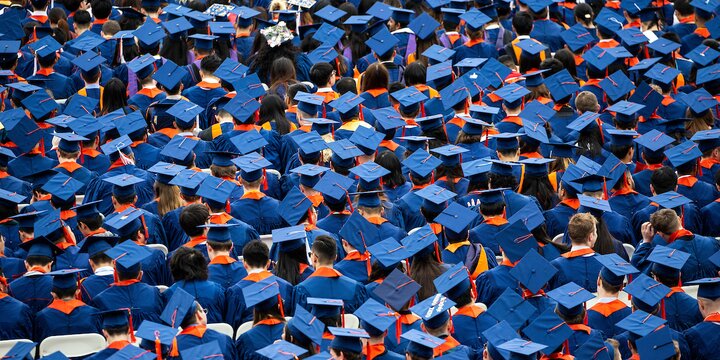A sea of Illinois graduates in regalia, caps and gowns, viewed from behind