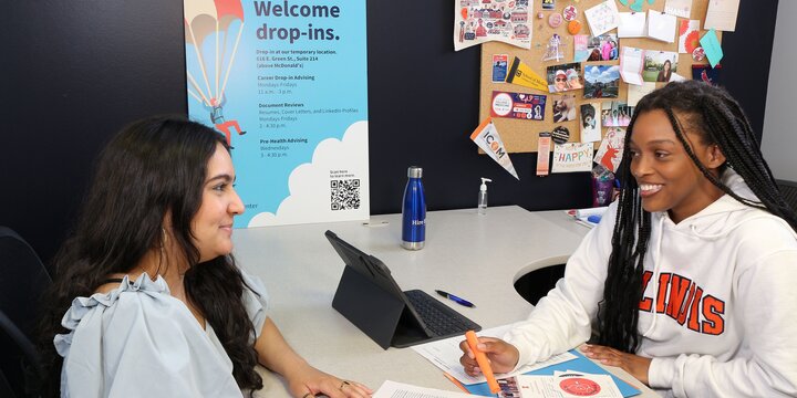 a pre-health ambassador meets with a student at a desk for pre-health drop-in hours